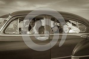 Family Waving Hello in Vintage Car