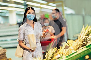 Family wearing face protective medical masks for protection from virus disease with shopping cart buying food at supermarket