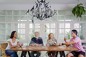 Family wearing face sheild enjoying playing card together at home