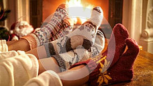 Family wearing knitted woolen socks warming feet at fireplace on Christmas eve