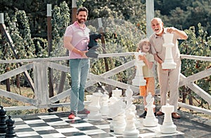 Family weekend. Happy grandfather father and son playing chess. Men in different ages playing chess board game. Three