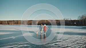 Family weekend spend time together. Happy young couple walking on winter frozen lake with their doggy. Xmas holidays