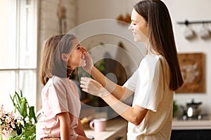 Family weekend. Young woman attractive mother touching face of her small cute daughter and smiling while spending time together at