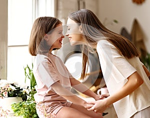 Family weekend. Young woman attractive mother touching face of her small cute daughter and smiling while spending time together at