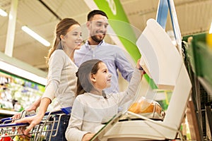 Family weighing oranges on scale at grocery store