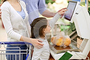 Family weighing oranges on scale at grocery store