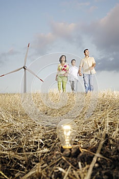 Family and wind turbines, light bulb in the ground