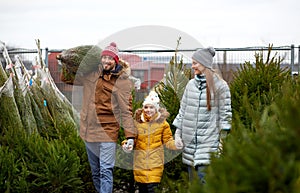 Happy family buying christmas tree at market