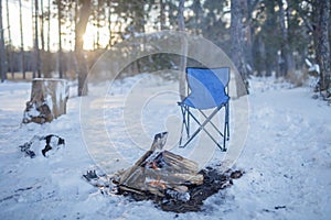 Family winter picnic. Bonfire and camping chair, winter walk in snowy forest on weekend, horizontal