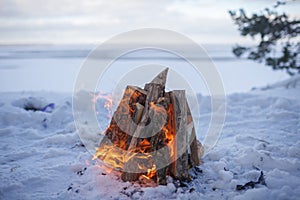 Family winter picnic. Bonfire on the shore of a frozen lake during a winter travel photo