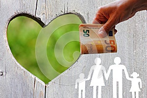 Family on wooden background with green heart and money in hand