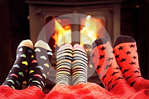 Family in woolen socks warming feet by fire in winter