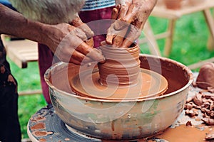 Family working on pottery wheel. Master teaching kid to creating on the pottery wheel. Craftsman`s hands and child