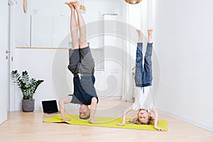 Family yoga at home on a mat. dad and son doing unassisted headstands