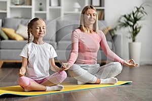 Family Yoga. Mother And Little Daughter Meditating Together At Home