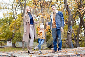 A family with a young boy in the autumn forest walk