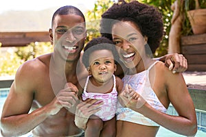 Family With Young Daughter Having Fun On Holiday In Swimming Pool Together