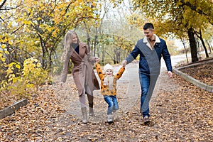 A family with a young son walk in the Park in autumn