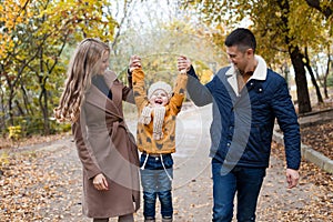 A family with a young son walk in the Park in autumn