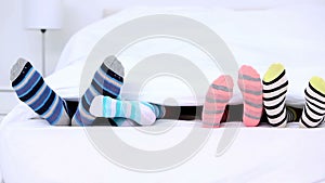 Familys feet in stripey socks kicking under the covers