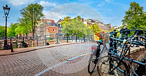 Famous Amsterdam in one photo - leaning houses, bridges, canals, bicycles and lanterns. Panorama of the famous old center of