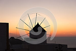 Famous attraction of Oia village at sunset with windmill in Santorini Island