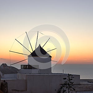 Famous attraction of Oia village at sunset with windmill in Santorini Island