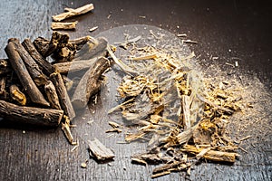 Famous ayurvedic herb Licorice root or Mulethi on wooden surface along with its powder.