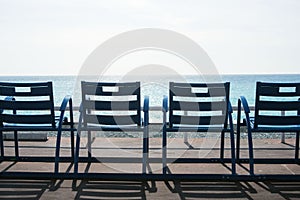Famous blue chairs on the Promenade des Anglais of Nice, France against the backdrop of the blue sea.