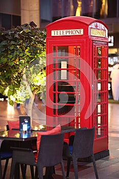 The famous British red telephone booth in London next to a cozy street cafe