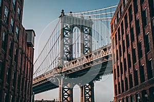 Famous Brooklyn Bridge between two buildings against the blue sky