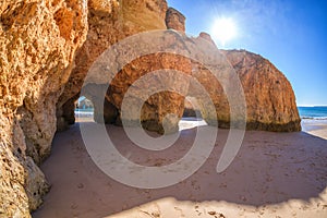 Famous caves in a beach rock formation in Algarve, Portugal. After two caves you can see the ocean, the sun is shining above the