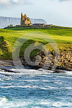 Famous Classiebawn Castle in picturesque landscape of Mullaghmore Head. Spectacular sunset view with waves rolling ashore.