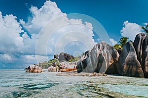 Famous granite boulders in lagoon with shallow ocean water and white cloudscape on amazing Anse Source D`Argent tropical