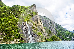 Famous Hengjanefossen waterfall coming down from a steep rock face into Lysefjord.