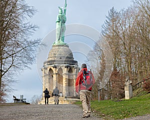 The famous Hermann Monument is located near Detmold. In the foreground a hiker with a backpack.