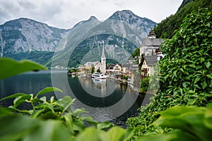 Famous lake side view of Hallstatt village with Alps behind, Foliage leaves framed. Austria