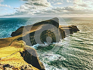 Famous look at Lighthouse on the cliff of Neist Point, rocky coast on the Isle of Skye