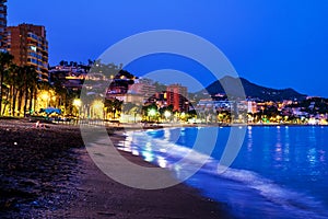 Famous Malagueta beach in Malaga, Spain at night. Coastline and motion blurred waves at sunset