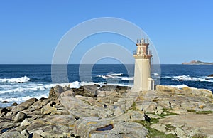 Famous Muxia Lighthouse located at Camino de Santiago pilgrimage with blue sky and wild sea with waves. Coruna, Spain.