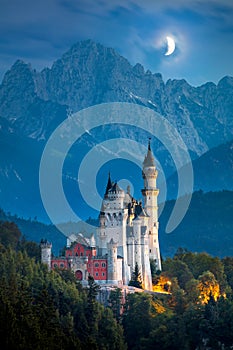 Famous Neuschwanstein Castle at night with moon and illumination