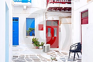 Famous old town narrow street with white houses and red door. Mykonos island, Greece