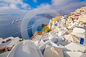The famous panoramic view of the sights of Santorini - white houses, blue domes and yachts in the azure sea. Oia, Santorini island