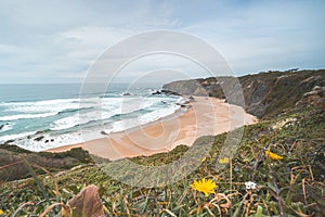 Famous Praia dos Machados beach in Odemira, western Portugal. The rocks surrounding the moon-shaped sandy beach with large waves