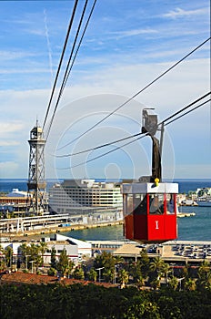 Famous red cablecar with people over the port in Barcelona. Transportation from Montjuic to the harbor of Barcelona