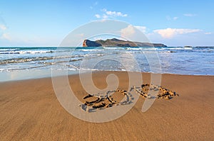 Famous resort of Crete island, Greece. Sand beach seascape with the rays of the sun. 2019 writing on the surface. Beautiful sea