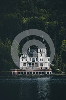 Famous schloss lake Grundlsee, Villa Castiglioni in green forest reflected in water.