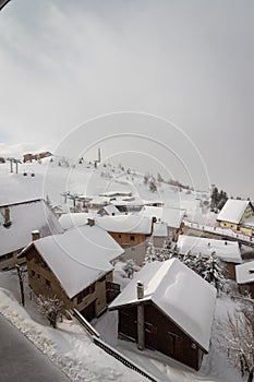 The famous ski town of Alpe d`Huez in the French Alps. Wooden houses are covered with snow and fog in the morning