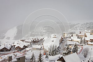 The famous ski town of Alpe d`Huez in the French Alps. Wooden houses are covered with snow and fog in the morning