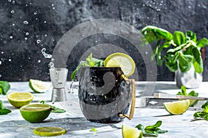 Famous splashing Moscow mule alcoholic cocktail in copper mugs with lime, lime, ginger beer, vodka and mint, freeze motion